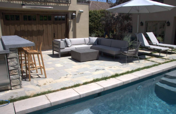 A beautifully landscaped garden featuring a flagstone pathway, water feature, and retaining wall with natural stone accents.