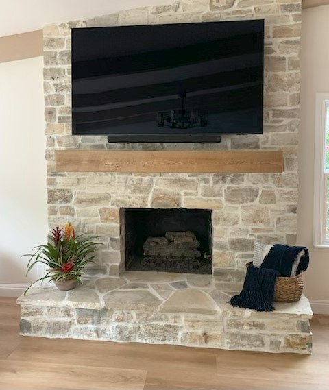 Living room interior wall finished with natural thin stone veneer in warm beige and gray tones.