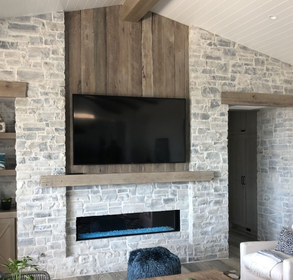 Living room interior wall finished with natural thin stone veneer in warm beige and gray tones.